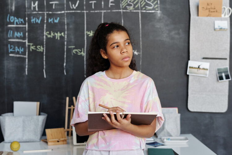girl thinking, holding notebook and pencil