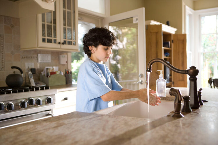 child washing hands in kitchen