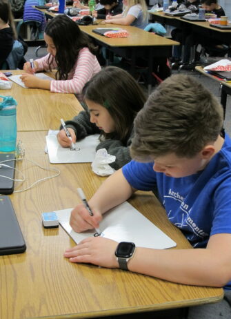 Students writing on paper in classroom